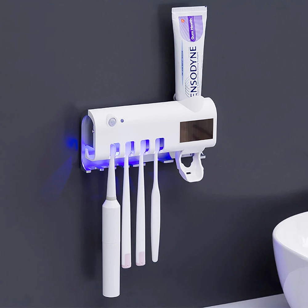 UV Light Sterilizer Toothbrush Holder Cleaner & Automatic Toothpaste Dispenser mounted on a wall with toothbrushes and toothpaste.