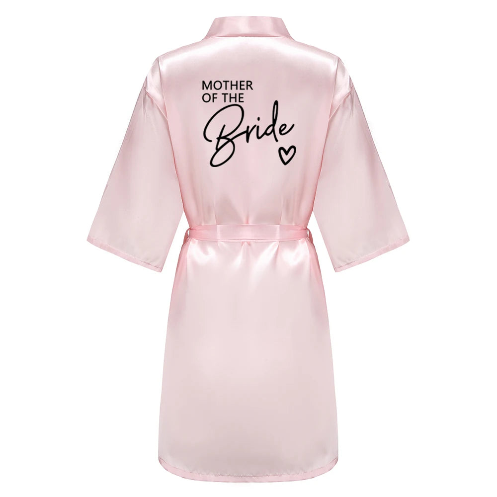 Bridesmaid satin robes in soft pink satin with 'Mother of the Bride' printed on the back, perfect for wedding celebrations.