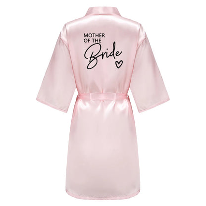 Bridesmaid satin robes in soft pink satin with 'Mother of the Bride' printed on the back, perfect for wedding celebrations.