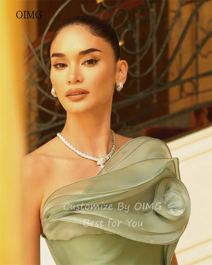 Model wearing a green strapless mermaid prom gown by OIMG, showcasing satin fabric and elegant design details.
