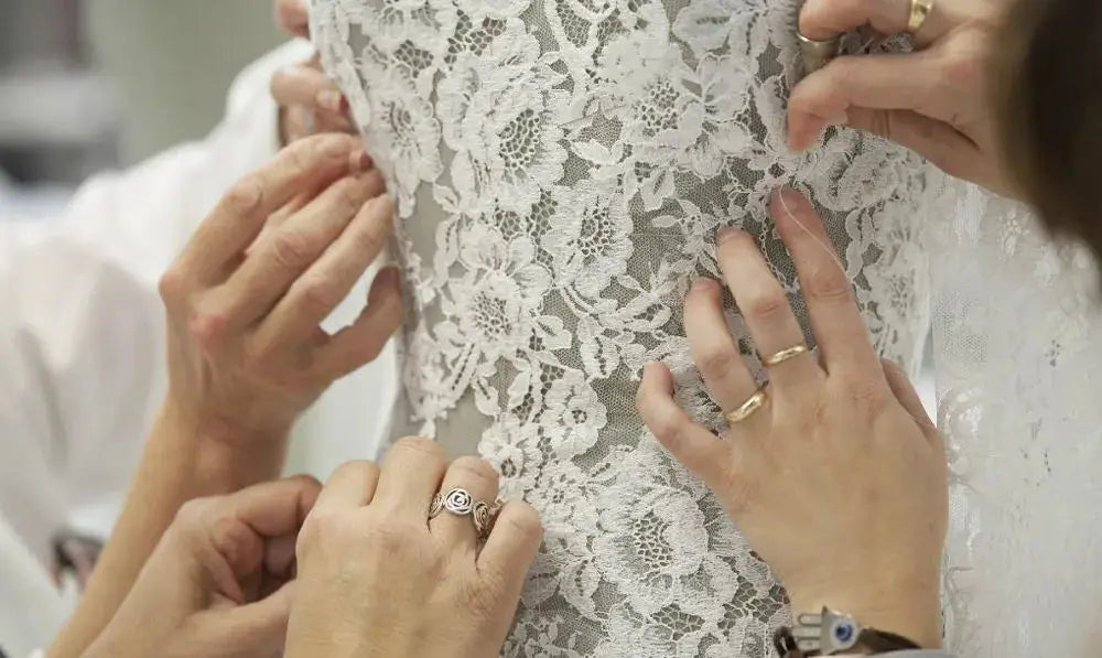 Hands adjusting lace detailing on a formal gown, showcasing the craftsmanship in elegant evening dresses with 3D flowers.