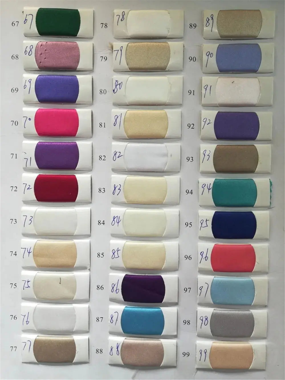 Color swatches for fabric, showcasing various shades numbered for identification, ideal for custom dress design.