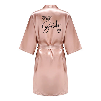 Bridesmaid satin robes in a soft pink color, featuring 'MOTHER OF THE BRIDE' text on the back.