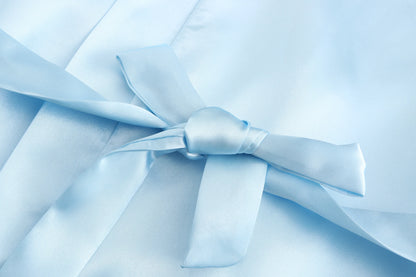 Light blue satin fabric with a tied bow detail, showcasing a wedding party satin robe design for brides and bridesmaids.