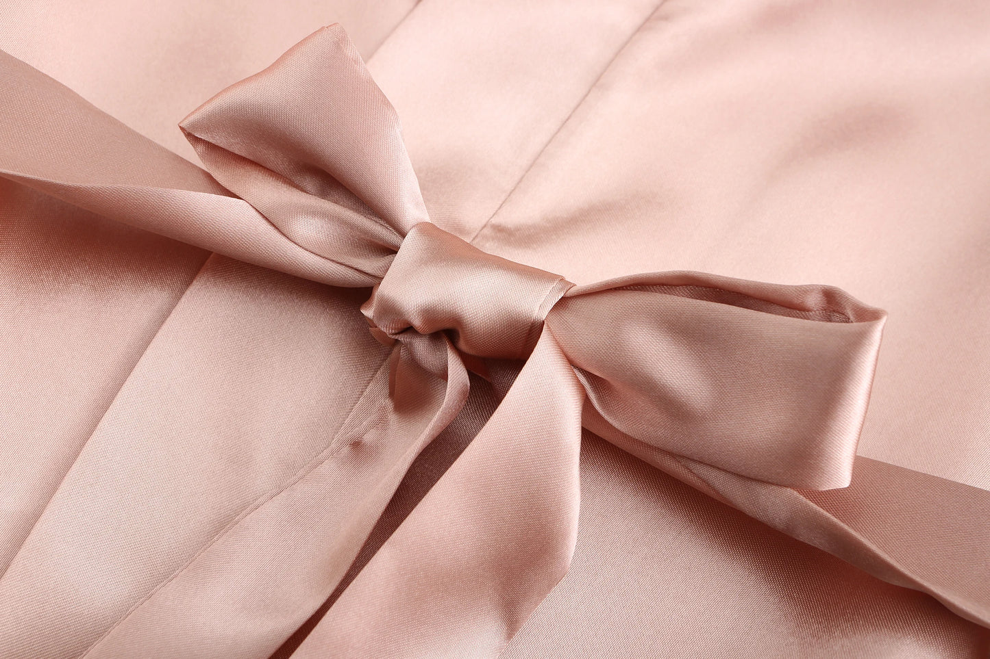 Close-up of a satin bow on a soft pink bridesmaid satin robes fabric, highlighting elegance and comfort.