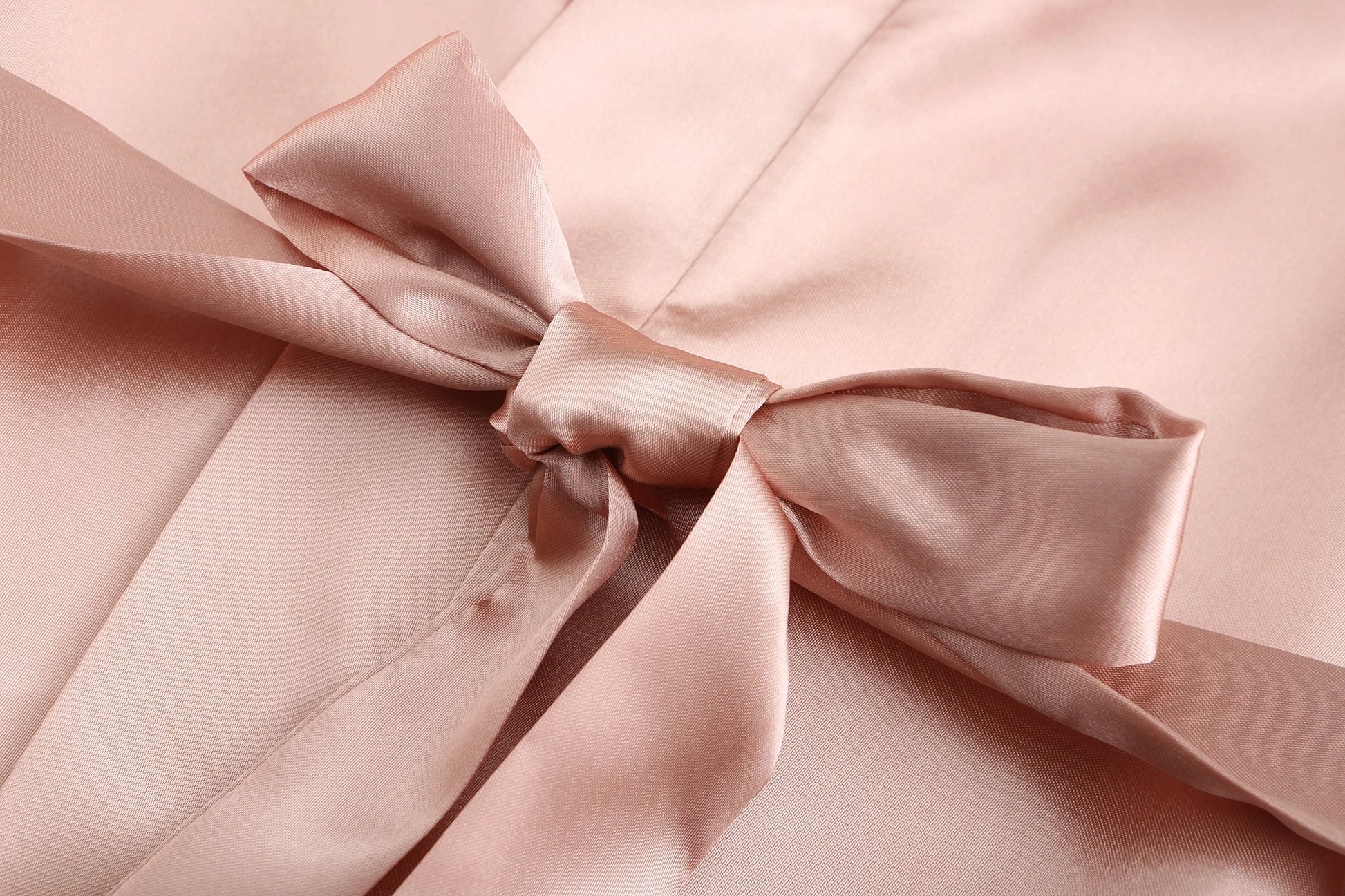 Close-up of a satin bow on a soft pink bridesmaid satin robes fabric, highlighting elegance and comfort.