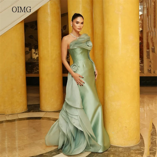 Green strapless mermaid prom gown showcased in a sleek satin fabric with tiered design and elegant floral detail.