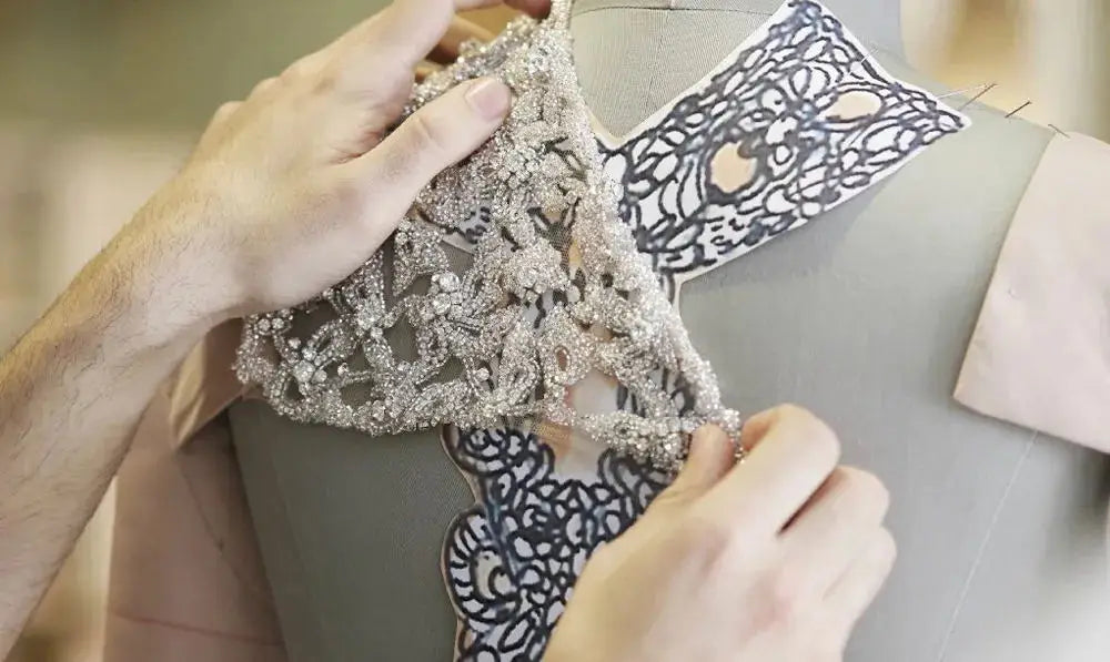 Crafting elegant evening dresses with 3D flowers, showcasing delicate beaded lace detail on dress fabric.
