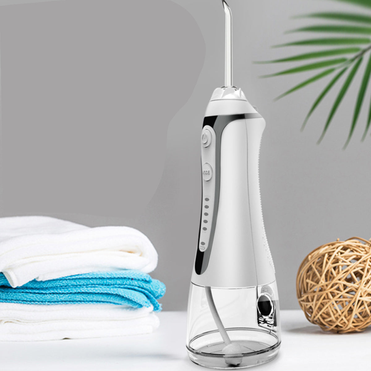 Portable Water Flosser And Pik For Dental Hygiene on a bathroom counter with towels and decor.